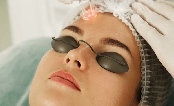 A dermatologist performing laser treatment on face
