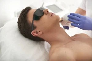 A therapist performing mens laser hair removal treatment in a sterilized room