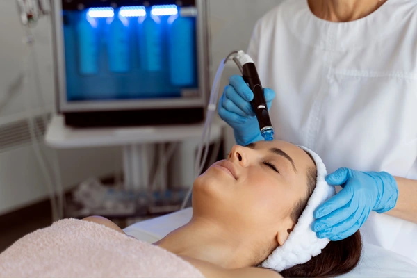 A therapist performing hydrafacial treatment